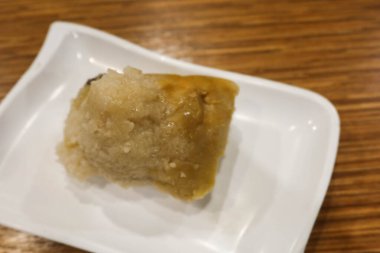 Domuz eti, mantar ve tuzlanmış yumurta sarısı ile doldurulmuş pirinç hamur köftesini fotokopi alanı ile birlikte beyaz bir tabağa koy.