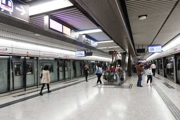 Merkez, Hong Kong - 25 Ocak 2025: MTR treni Tsuen Wan Hattı Platformu, yürüyen merdivende bekleyen ve inen yolcularla birlikte.