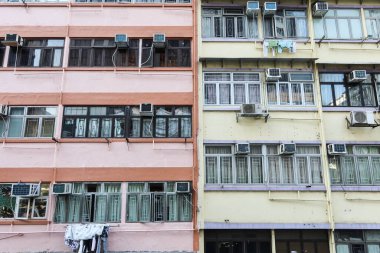 Mong Kok, Hong Kong. 28 Ocak 2025. Ön cephesinde pembe ve bej renkli duvar, pencere ve klima bulunan yaşlılık, aşınma ve yırtılma. Yarı Pembe ve yarı Sarı boyalı cephe. 