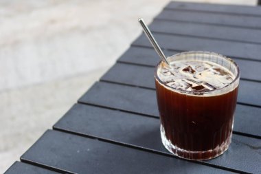 Piknik masasının üzerine ekolojik paslanmaz çelik pipetle fotokopi alanı olan buzlu Americano sade bir kahve koyun.