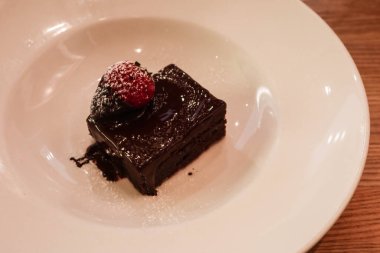 Çikolata soslu çikolatalı brownie 'ye yakın, üstüne de beyaz bir tabakta fotokopi alanı olan çilek.