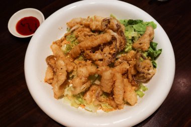 Çin yağda kızartılmış biber tuzlu kalamarının yanına beyaz tabak ve yanında sos koyun.