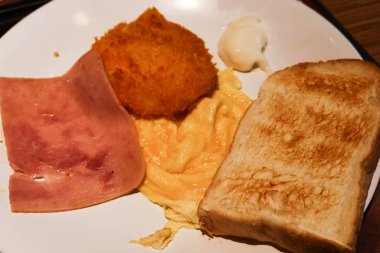 Hong Kong usulü kahvaltı, jambon, tost, çırpılmış yumurta ve kızarmış morina balığı. Salata soslu mayonez.