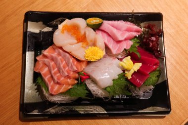 Japon çiğ saşimi balık tabağını dilimlere ayırın. Somon, ton balığı, karides, istiridye, plastik bir kutuda süslemeli çiçek ve yaprak ve fotokopi alanı.