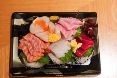 Japon çiğ saşimi balık tabağını dilimlere ayırın. Somon, ton balığı, karides, istiridye, plastik bir kutuda süslemeli çiçek ve yaprak ve fotokopi alanı.