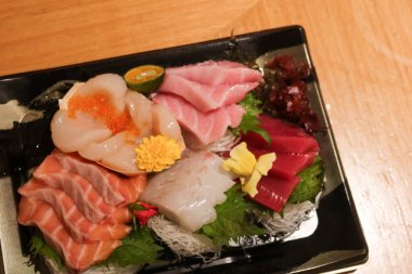 Japon çiğ saşimi balık tabağını dilimlere ayırın. Somon, ton balığı, karides, istiridye, plastik bir kutuda süslemeli çiçek ve yaprak ve fotokopi alanı.