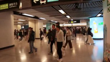 Amirallik, Hong Kong - 5 Nisan 2025: Metroyla dolu MTR tren istasyonu platformu ve yürüyen ve geçen yolcular. Tavanda ve LED sütunda asılı Çince ve İngilizce dizin işareti