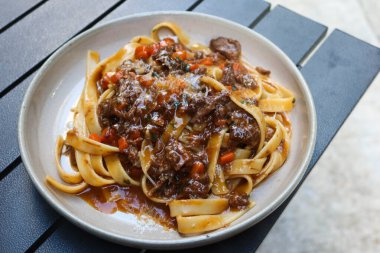 Açık hava kamp masasında fotokopi alanı olan kırmızı şarap soslu fettuccine makarna.