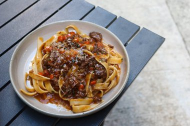Açık hava kamp masasında fotokopi alanı olan kırmızı şarap soslu fettuccine makarna.