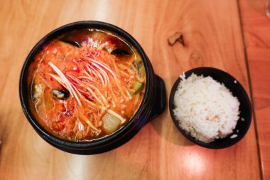 Kore kimchi tofu soya fasulyesi, deniz ürünleri kasesi ve yanında bir kase pilav.