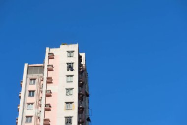 Ho Man Tin, Hong Kong - 25 Ocak 2025: Mavi gökyüzünde, üzerinde fotokopi alanı olan pembe ve beyaz bir bina