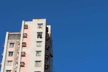 Ho Man Tin, Hong Kong - 25 Ocak 2025: Mavi gökyüzünde, üzerinde fotokopi alanı olan pembe ve beyaz bir bina