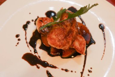 Karamelli elma ve beyaz tabakta siyah sirke sosu ile foie gras yakın çekim