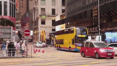 Merkez, Hong Kong - 4 Nisan 2025: otobüs, taksi ve geçen araçlarla dolu trafik yolu. İnsanlar yol ayrımını bekliyor..