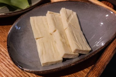 Pişmemiş çiğ soya peynirini (soya peyniri) sıcak tencere şeklinde bir tabakta dikdörtgen halinde kes