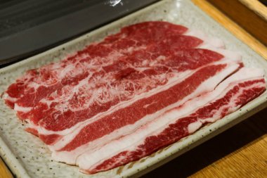 Pişmemiş çiğ sığır eti dilimlerini yakın, sıcak tencereye ya da pişmeye hazır. Fotoğrafta kopyalama alanı var..