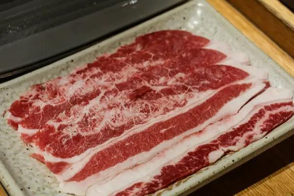 Pişmemiş çiğ sığır eti dilimlerini yakın, sıcak tencereye ya da pişmeye hazır. Fotoğrafta kopyalama alanı var..