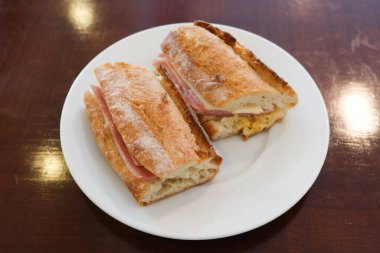 Jambonlu ve peynirli ekmekli sandviçin yarısı beyaz tabakta, fotokopi alanı ile kesilmiş.