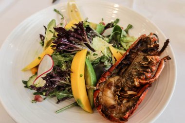 Salatayı mango, turp, lahana ve yarım ızgara ıstakozla kaplayın. 