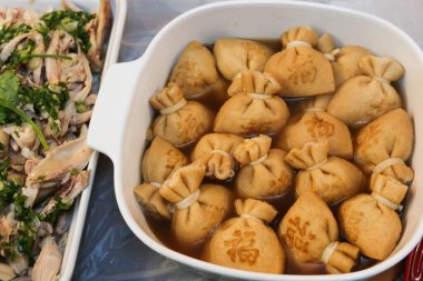 Büyük bir kap haşlanmış Japon tofu (soya peyniri) kesesine yakın pirinç keki (mochi kinchaku) ve Japonca bir kelime olan 