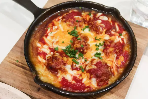 Domates soslu fırında köfte ile ahşap yalıtım tahtasında peynir sosu.