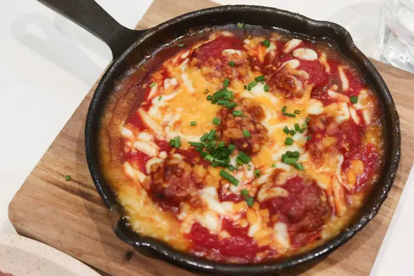 Domates soslu fırında köfte ile ahşap yalıtım tahtasında peynir sosu.