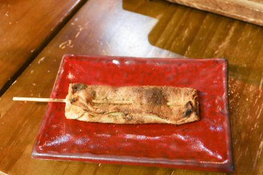 Kanton şişi ızgara tofu derisini ahşap bir masada kırmızı bir tabakta yakın. 