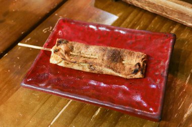 Kanton şişi ızgara tofu derisini ahşap bir masada kırmızı bir tabakta yakın. 