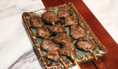 Izakaya restoranında bir tabakta üç şişe ızgara tavuk taşağı yakın. 