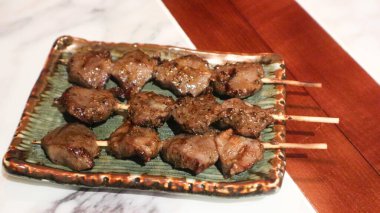 Izakaya restoranında bir tabakta üç şişe ızgara tavuk taşağı yakın. 