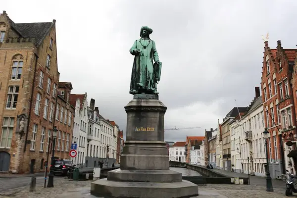 Jan Van Eyck heykeli, Brugge, Belçika - 15 Mar 2016: Bulutlu bir günde çekilmiş heykel yan tarafında sıra sıra lonca evleri var