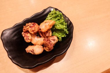 Japon küçük kızartılmış kalamar parçalarını fotokopi alanı olan siyah bir tabakta kapatıyoruz.