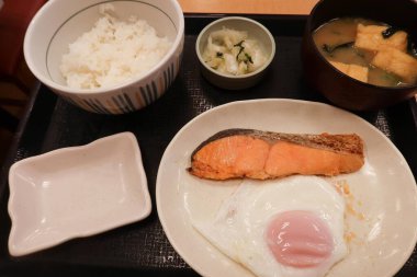 Japon usulü kahvaltıda ızgara somon ve tavada kızartılmış güneşte yumurta, bir kase pilav ve miso çorbası.