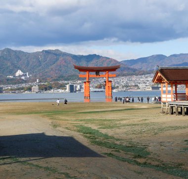 Itsukushima Tapınağı, Miyajimacho, Hatsukaichi, Hiroshima - 8 Aralık 2024: Bulutlu bir günde deniz kenarında yüzen kırmızı torii kapısı