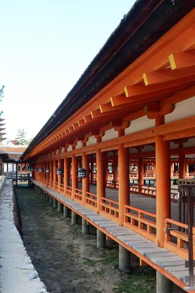 Itsukushima Tapınağı, Hatsukaichi, Hiroşima, Japonya - 9 Aralık 2024: UNESCO dünya mirası tapınağı kırmızıya boyanmış. Ahşap sütunlar parlak turuncu bir renge boyanmış. Binada yükseltilmiş bir yürüyüş yolu ve 