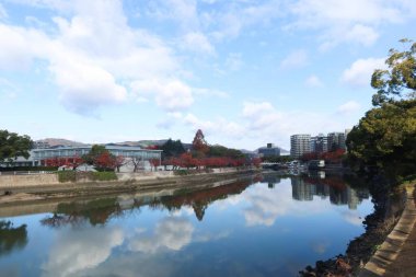 Motoyasu Nehri, sonbaharda parkın yansımasıyla kırmızı ve sarı yaprakları gösteriyor.
