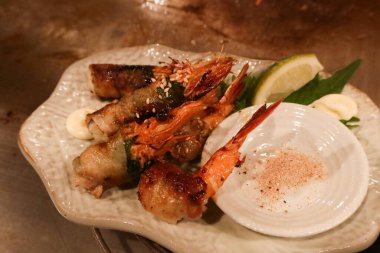 Tuzlu bir tabakta soya peyniri kabuğuyla sarılmış ızgara karidesleri kapatın.