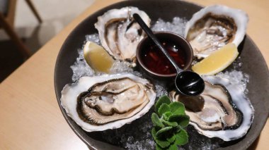 Dört parça taze çiğ istiridyeyi sirke ve limon dilimiyle kaplayıp büyük bir tabakta fotokopi alanına koyun.