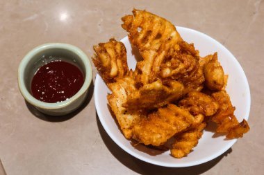 Kızarmış patatese yakın, kıtır kıtır, yanında domates ketçaplı aperatifler.