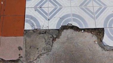 Döşeme bölümünün bir kısmını kırmızı kiremit karışımı bir ızgara deseni ve dalgalı eğimli beyaz kiremitlerle kaplayın. Kırık kiremitler ve enkaz parçaları etrafa saçılmış..