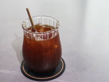 Beyaz bir masada, üzerinde fotokopi alanı olan bir bardak buzlu siyah amerikan kahvesi.