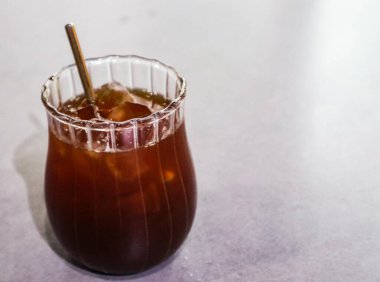 Beyaz bir masada, üzerinde fotokopi alanı olan bir bardak buzlu siyah amerikan kahvesi.