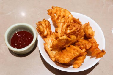 Kızarmış patatese yakın, kıtır kıtır, yanında domates ketçaplı aperatifler.