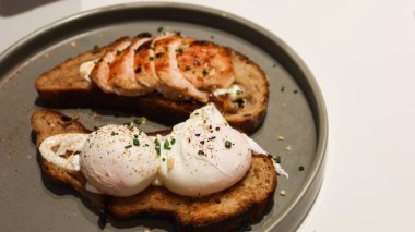 Haşlanmış yumurtayı bir tost ekmeğine ve tavuk göğsünü başka bir dilime kopyalama alanı olan gri bir tabağa koy.