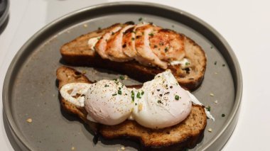 Haşlanmış yumurtayı bir tost ekmeğine ve tavuk göğsünü başka bir dilime kopyalama alanı olan gri bir tabağa koy.