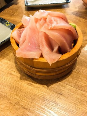Şişko Ton Balığı 'nın (chu toro) dikey fotoğrafı saşimi pirinci ahşap bir kasede dilimliyor, alttaki boşluğu kopyalıyor.