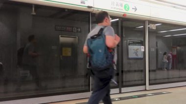 Ho Man Tin, Hong Kong - 6 Haziran 2025: MTR tren platformu cam kapılı ve yoldan geçen yolcu