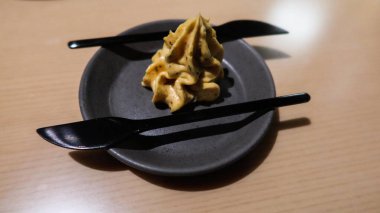 Kremsi bir altın rengine yakın ya da yanında iki siyah bıçakla krem şeklinde tereyağı.