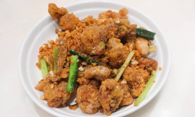 Kanton usulü bol yağda kızartılmış tuz ve biberli kalamarı beyaz tabakta sarımsak ile yakın.