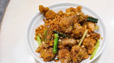 Kanton usulü bol yağda kızartılmış tuz ve biberli kalamarı beyaz tabakta sarımsak ile yakın.